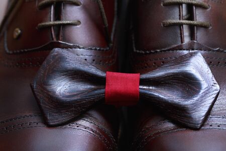 Wooden bow tie with red ribbon on the leather male shoes.の写真素材