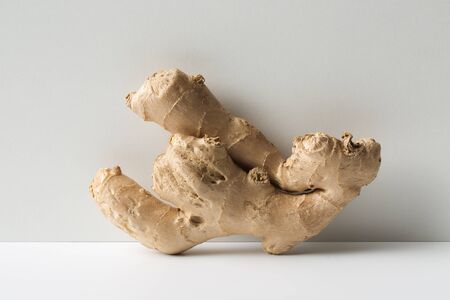 Cute fresh ginger root on white floor and grey wall.の写真素材