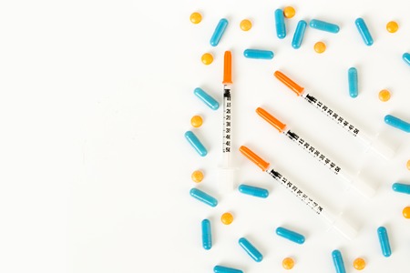 insulin syringe, pills and capsules on half of white background. Copy space.の写真素材
