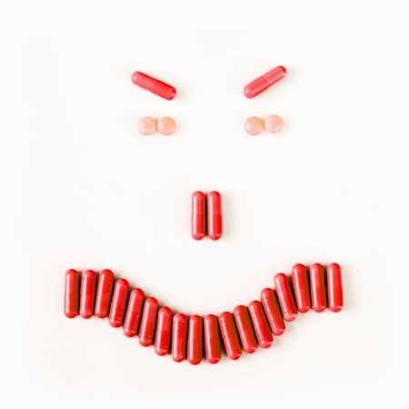 Angry smile made from many pills and capsules. wellness concept.