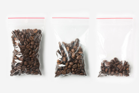 Set of three EMPTY, HALF AND FULL Plastic transparent zipper bag with coffee beans isolated on white. Vacuum package mockup with red clip. Concept.の写真素材
