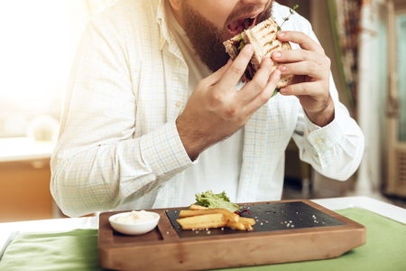 Portrait of man eating in cafe and enjoying food. A happy bearded man rejoices in a restaurant, consuming his food, which he ordered. The concept of restaurant business and service.の写真素材