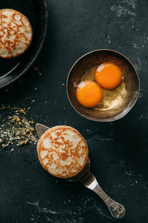 The process of cooking pancakes on a black background and set of ingredientsの写真素材