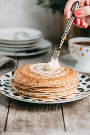 pancakes with butter and sour cream on light wooden background composition with flowers and teaの写真素材