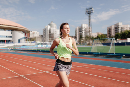 sporting a young girl in the gym and the stadium, warming up before exercise and listening to musicの写真素材