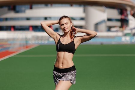 sporting a young girl in the gym and the stadium, warming up before exercise and listening to musicの写真素材