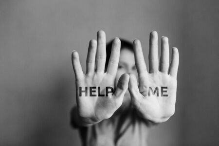 Domestic violence against women. The girl covers her face with her hand and asks for help. Stop domestic violence.の写真素材