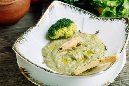 Restaurant dish with vegetable decor on a wooden background. Puree soup with mushrooms and sour cream on a plate.の写真素材
