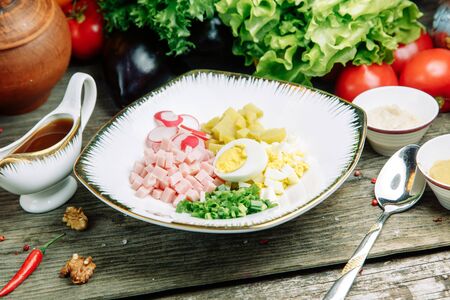 Restaurant dish on a wooden background with vegetables. Okroshka salad with kvass and horseradish on a plate.の写真素材