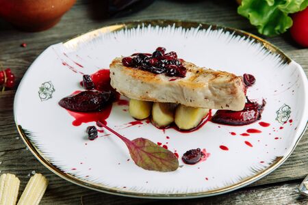 Restaurant dish on a wooden background with vegetables. Pork on the bone with sauce and garnish on a plate in pita bread.の写真素材