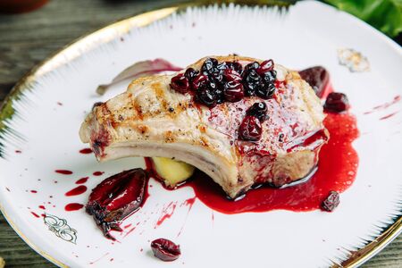 Restaurant dish on a wooden background with vegetables. Pork on the bone with sauce and garnish on a plate in pita bread.の写真素材