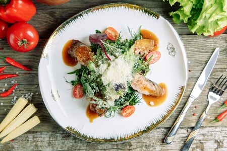 Restaurant dish on a wooden background with vegetables. Salad with beef tenderloin and arugula on a plate.の写真素材