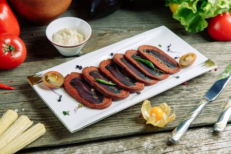 Restaurant dish on a wooden background with vegetables. Azerbaijani basturma with sliced spices.の写真素材