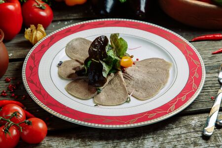Restaurant dish with vegetable decor on a wooden background. Beef cut-up on a plate with greens. の写真素材