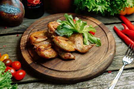 Restaurant dish with vegetable decor on a wooden background. Tobacco chicken with sauce and herbs on a plate.の写真素材