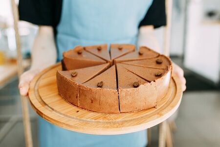 Cheesecake cut into slices in a coffee shop. Chocolate cake on a wooden Board.の写真素材