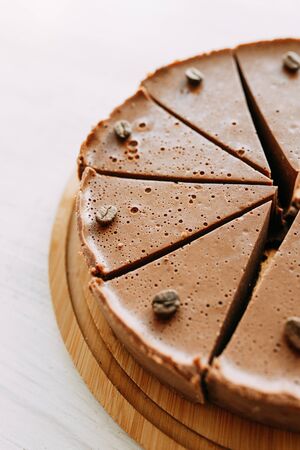 Cheesecake cut into slices in a coffee shop. Chocolate cake on a wooden Board.の写真素材