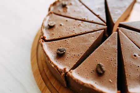 Cheesecake cut into slices in a coffee shop. Chocolate cake on a wooden Board.の写真素材