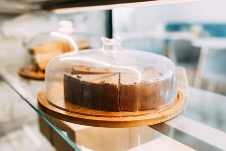 Cheesecake cut into slices in a coffee shop. Chocolate cake on a wooden Board.の写真素材