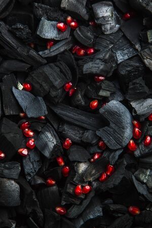 red fruit slices on a dark texture. blank for the menu background. Ripe pomegranate granules. Black charcoal background. の写真素材