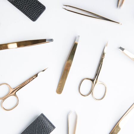 Scissors in a black leather case. Layout of Flatley tools. The set of tools of a cosmetologist. Tweezers on a white background.の写真素材
