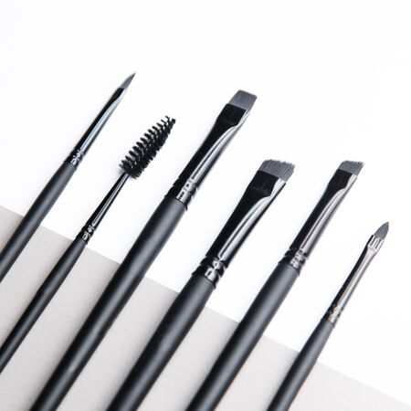  Light double background for the site. Tools for makeup artist. A set of makeup brushes. Black plastic eyebrow brush.の写真素材