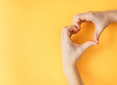 Yellow paper background. Medical issue and protection of human rights. A man's heart. Crossed arms in uniform. の写真素材