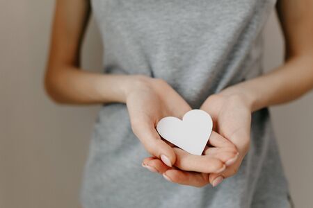 Gray t-shirt on the girl. Paper white heart, medicine. A heart from a woman's crossed arms. の写真素材