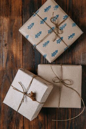 Wooden textured background. Gifts in Kraft packaging with ribbon.