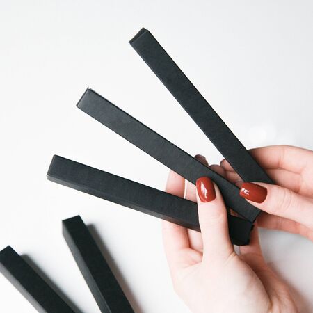  Hands with a set of Flatley brushes. Eyebrow and makeup brushes on white background.