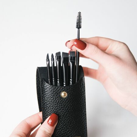  Hands with a set of Flatley brushes. Eyebrow and makeup brushes on white background.の写真素材