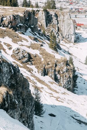 Spring snow melting on the mountain slopes. Winter mountains and stone slopes with snow. の写真素材