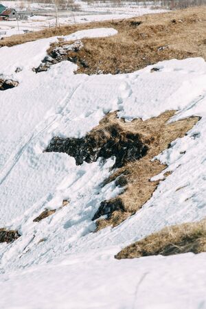 Spring snow melting on the mountain slopes. Winter mountains and stone slopes with snow. の写真素材