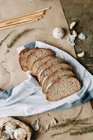  Garlic and thyme with pastries. A loaf of white rye bread. Sliced bread on a wooden Board. Slices on a towel.の写真素材
