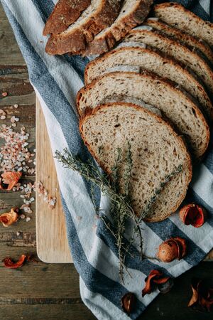  Garlic and thyme with pastries. A loaf of white rye bread. Sliced bread on a wooden Board. Slices on a towel.の写真素材