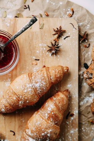 Flatley layout with nuts and powdered sugar. Croissants with raspberry jam. Fresh pastries on a wooden background. の写真素材