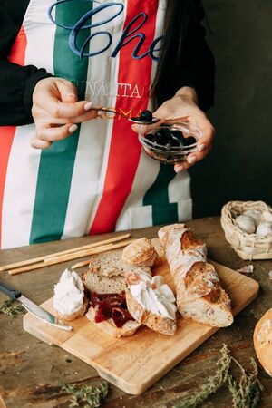 Making sandwiches on a wooden table. Home bread. The chef prepares bruschettas. Bread with cream cheese. の写真素材