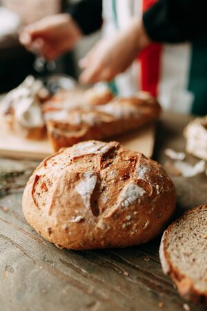  A loaf of white rye bread. Freshly baked bread. Girl's hands and cooking. Chef's table with pastries.の写真素材