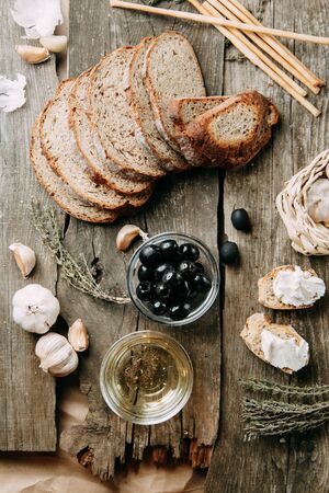 Sliced bread and garlic on a wooden background. Olives in a bowl of oil. Flatley's Italian food. の写真素材
