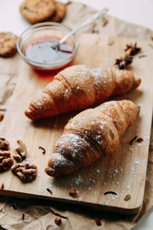 Flatley layout with nuts and powdered sugar. Croissants with raspberry jam. Fresh pastries on a wooden background. の写真素材