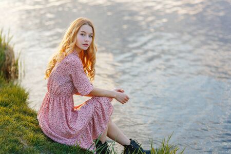  Sunny Golden portrait of a girl on vacation. Beautiful girl in a hat on the beach at sunset.の写真素材