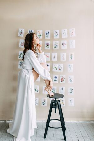 Portrait of the bride. Morning of the bride in a boudoir dress. Bright interior of the Studio with postcards.の写真素材