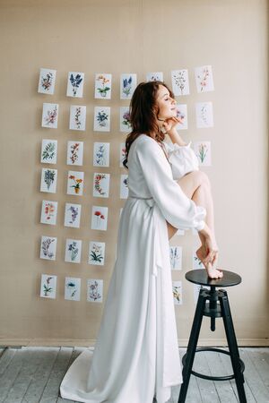 Portrait of the bride. Morning of the bride in a boudoir dress. Bright interior of the Studio with postcards.の写真素材