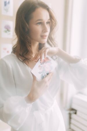Portrait of the bride. Morning of the bride in a boudoir dress. Bright interior of the Studio with postcards.の写真素材