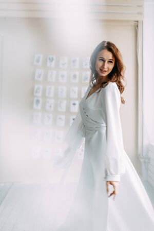 Portrait of the bride. Morning of the bride in a boudoir dress. Bright interior of the Studio with postcards.の写真素材