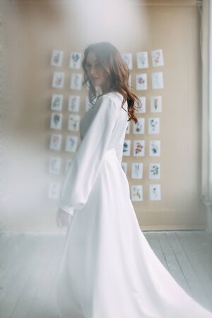 Portrait of the bride. Morning of the bride in a boudoir dress. Bright interior of the Studio with postcards.の写真素材