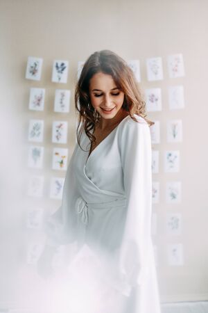 Portrait of the bride. Morning of the bride in a boudoir dress. Bright interior of the Studio with postcards.の写真素材