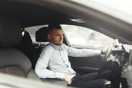 Conversations and phone calls, negotiations. Portrait of a young successful man in the car.の写真素材