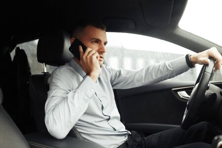 Conversations and phone calls, negotiations. Portrait of a young successful man in the car. 