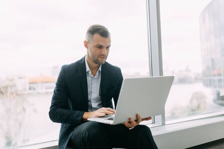 Office work, business situation. A young business man with a laptop in his hands.の写真素材